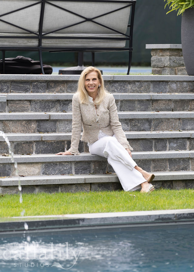 Beth sitting on stone steps by a pool